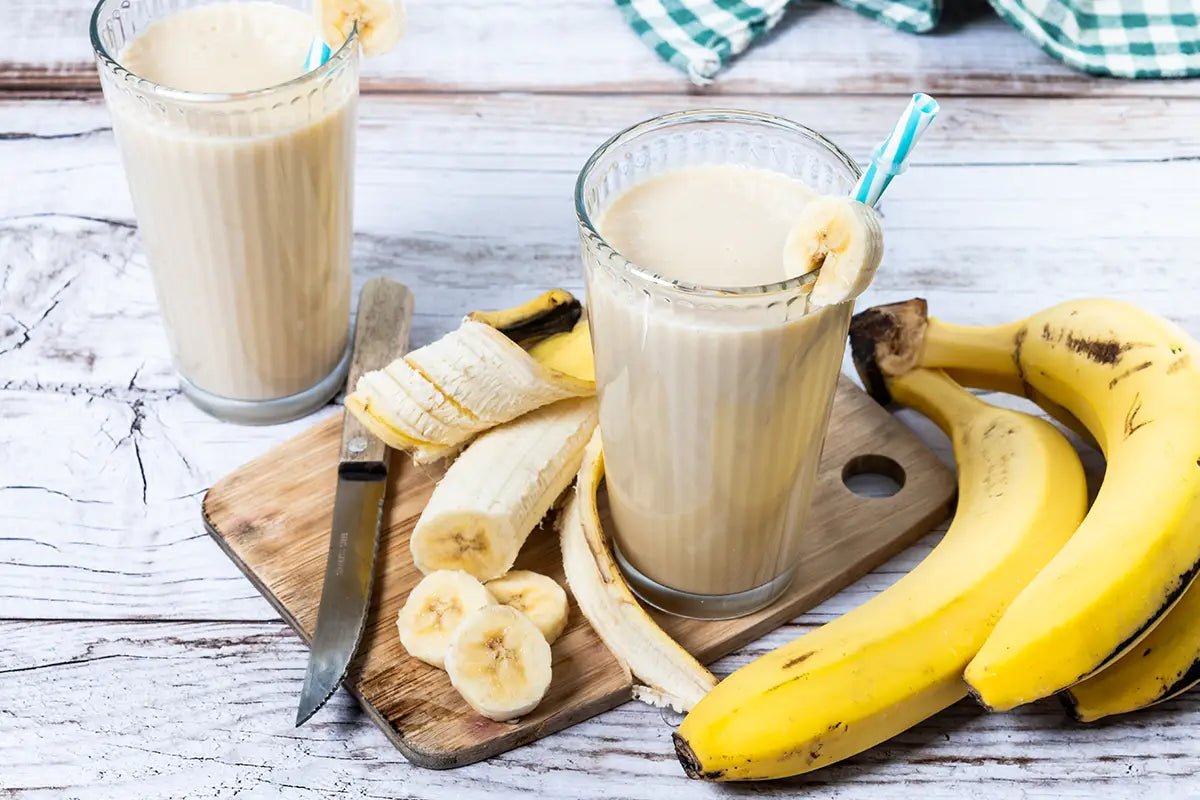frullato di banana in un bicchiere con casco di banane a lato