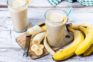 frullato di banana in un bicchiere con casco di banane a lato
