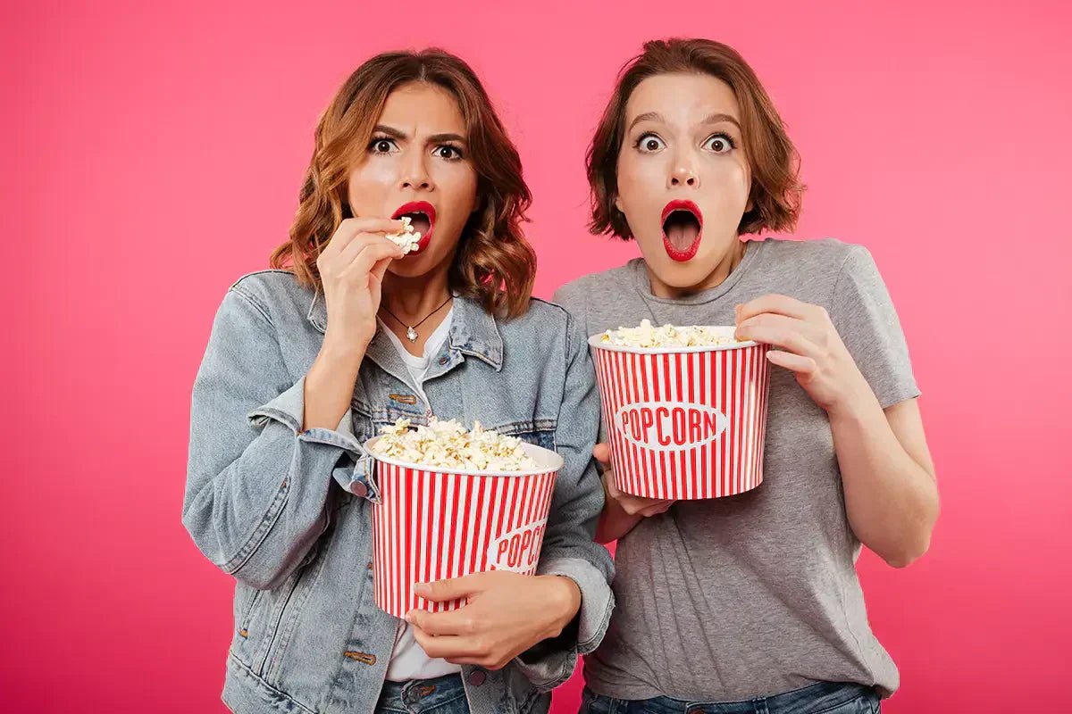 Ragazze mangiano pop corn con espressione stupita