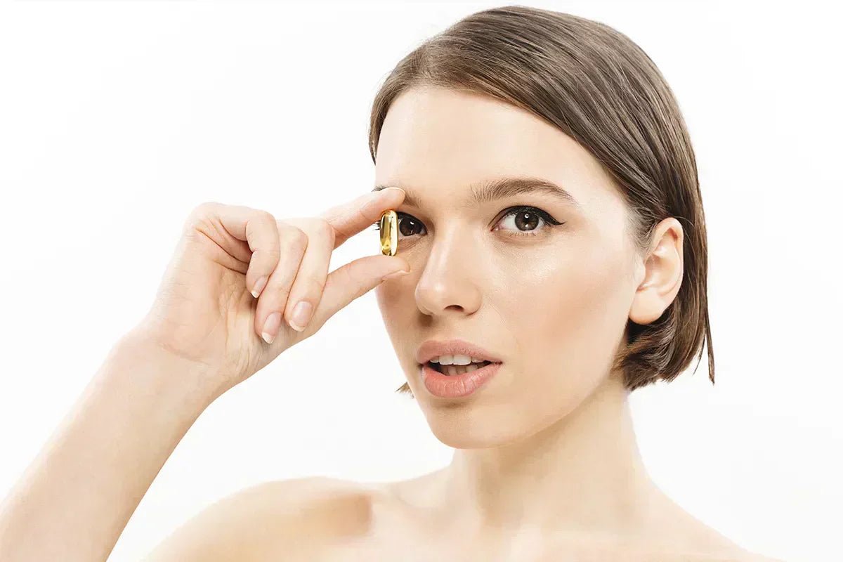 ritratto di ragazza che tiene capsula di olio di pesce vicino a un occhio